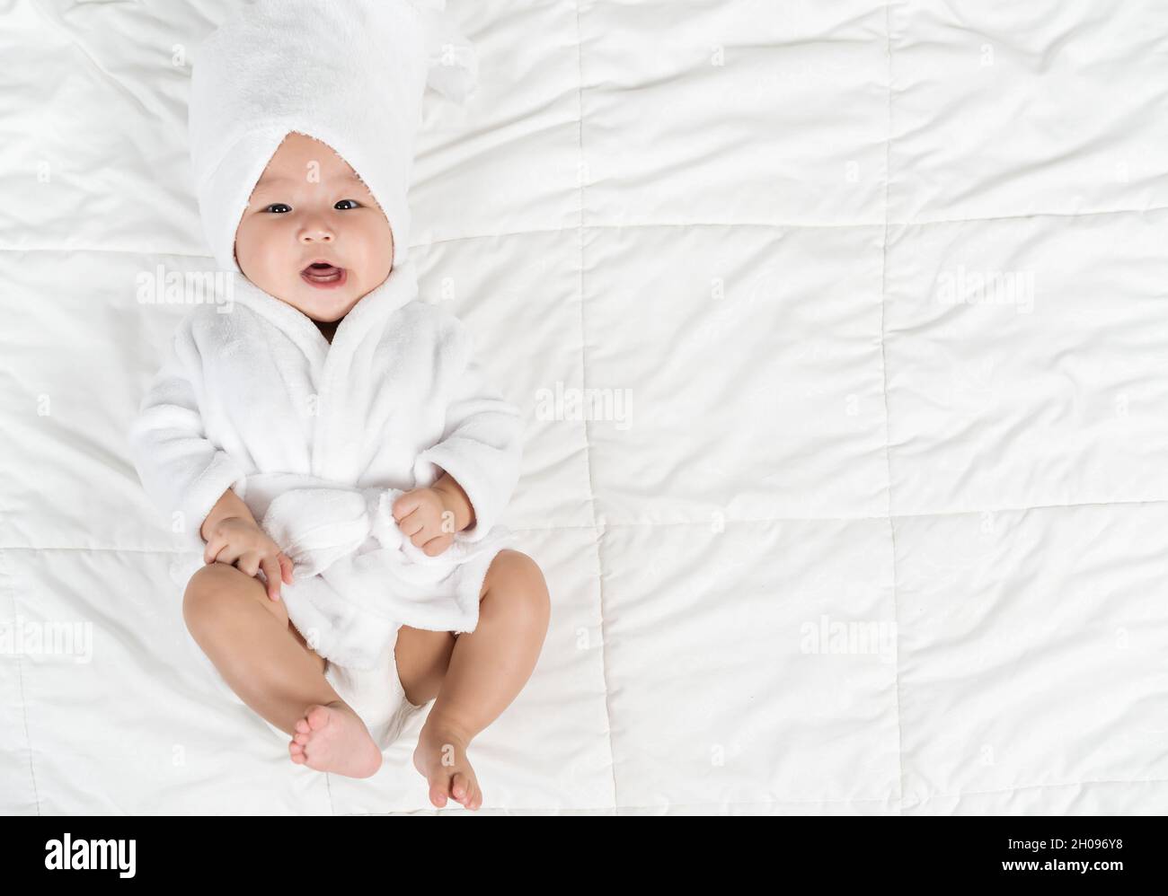 happy baby in soft bathrobe on a bed Stock Photo