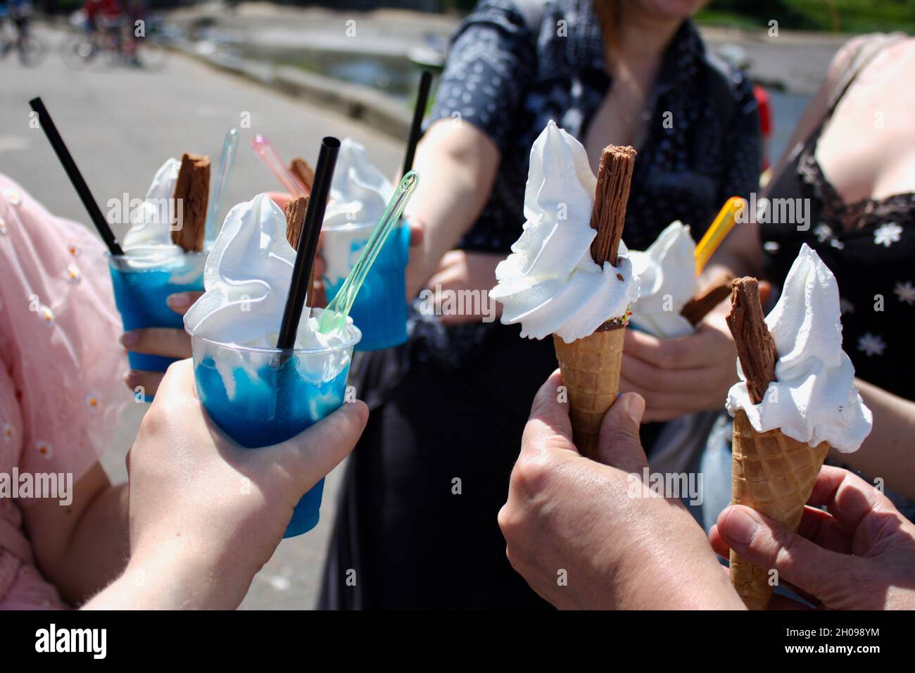 A group of people on holiday hold ice creams and slushie drinks in a circle Stock Photo