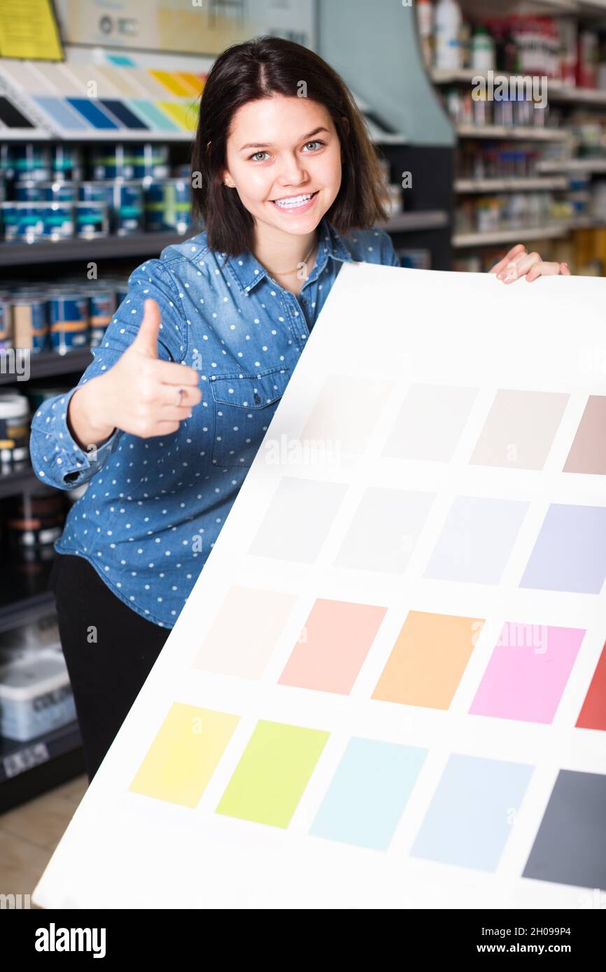 smiling female customer examining color scheme variants in paint store Stock Photo