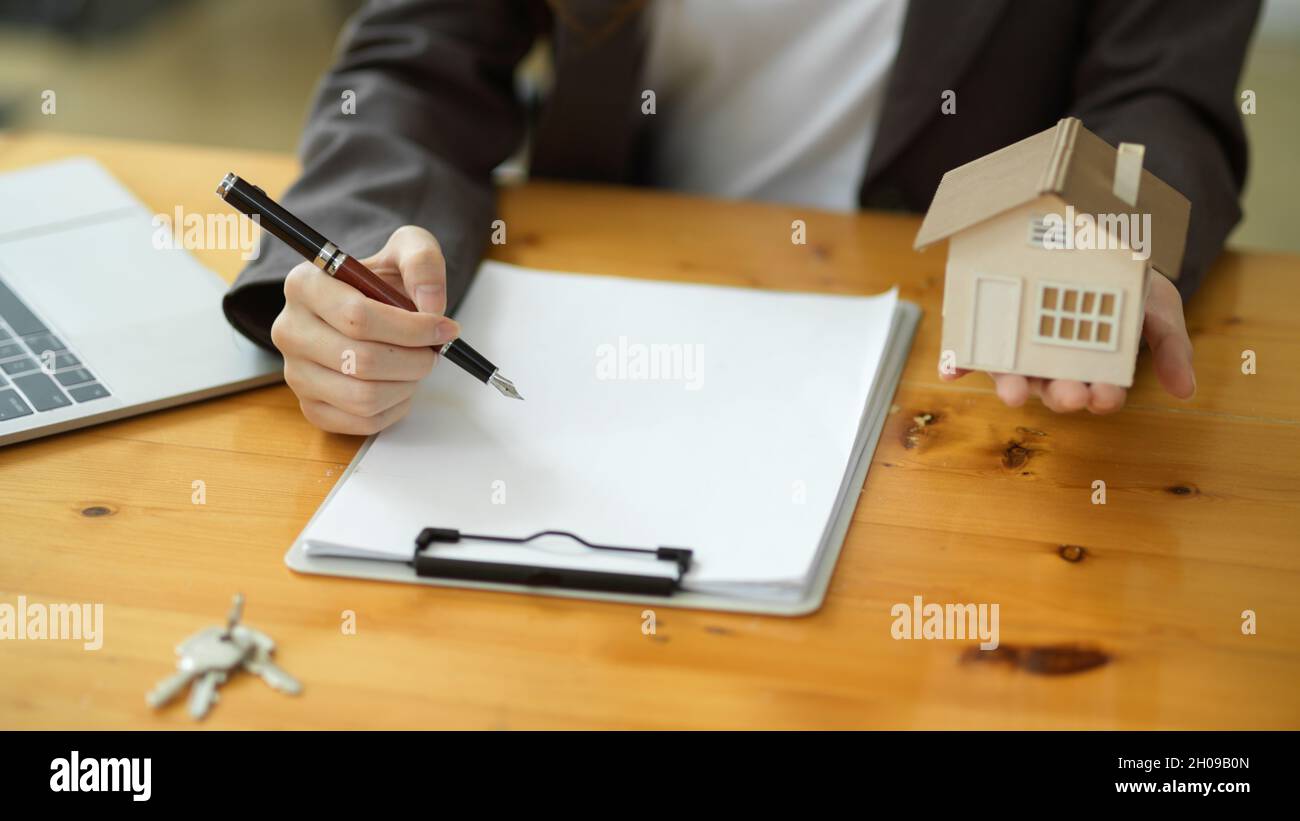 A female real estate agent drafts a rental agreement contract paper and ...