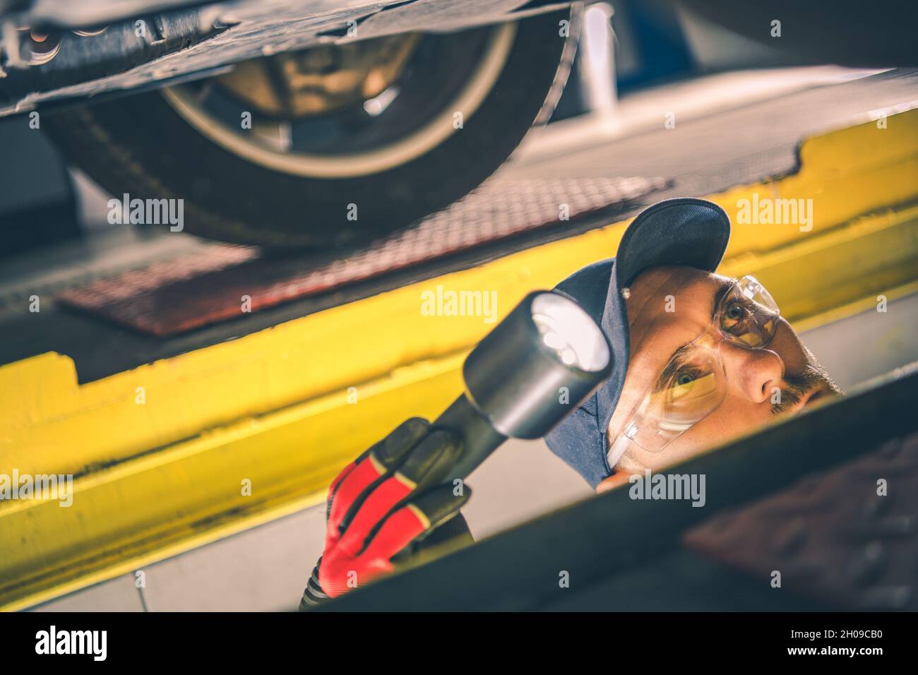 Automotive Industry Theme. Caucasian Car Mechanic with Flashlight in