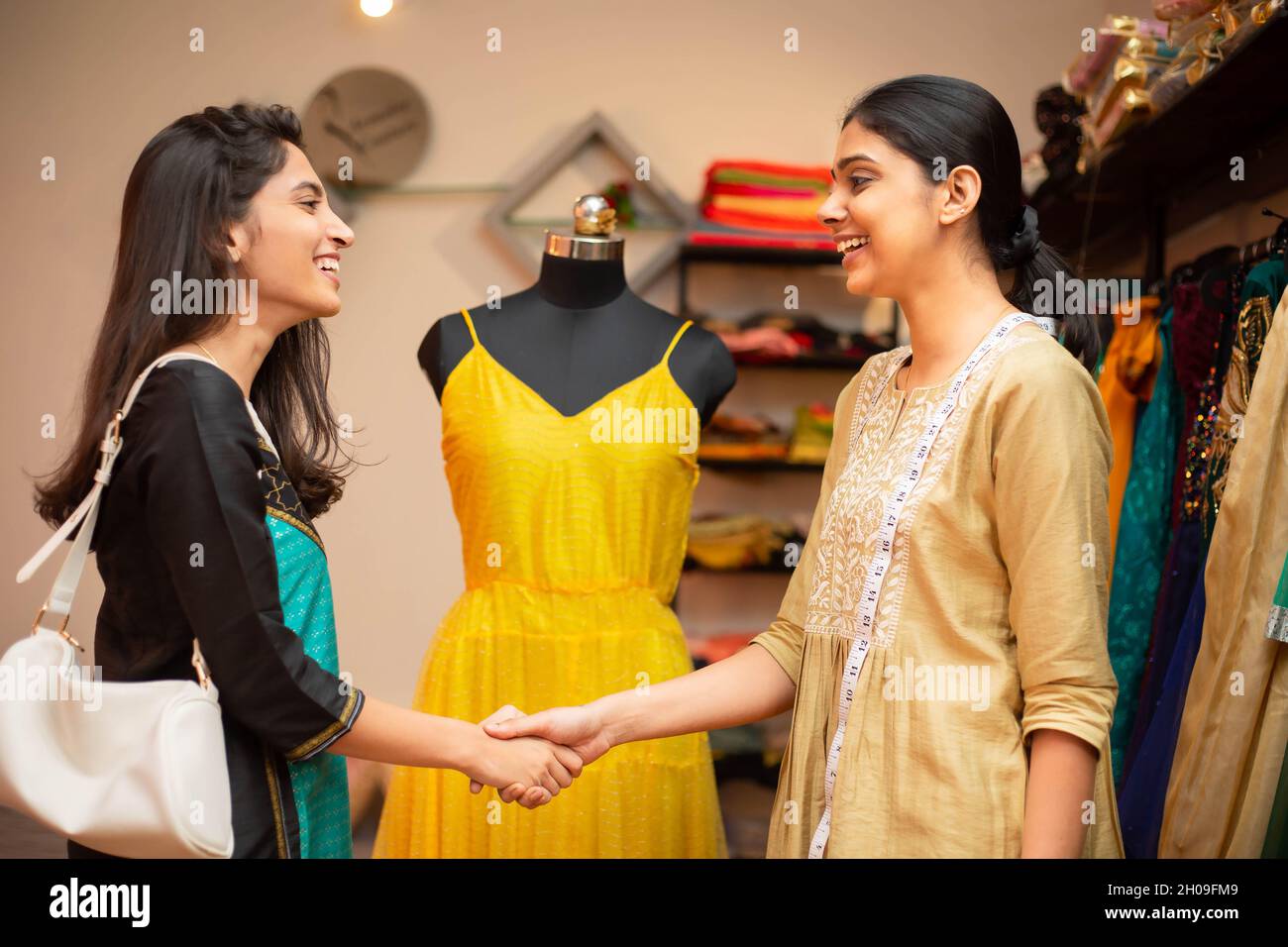Young happy indian woman,tailor,smiling fashion designer and customer or client shaking hands over done deal,successful order completed,showcasing on Stock Photo