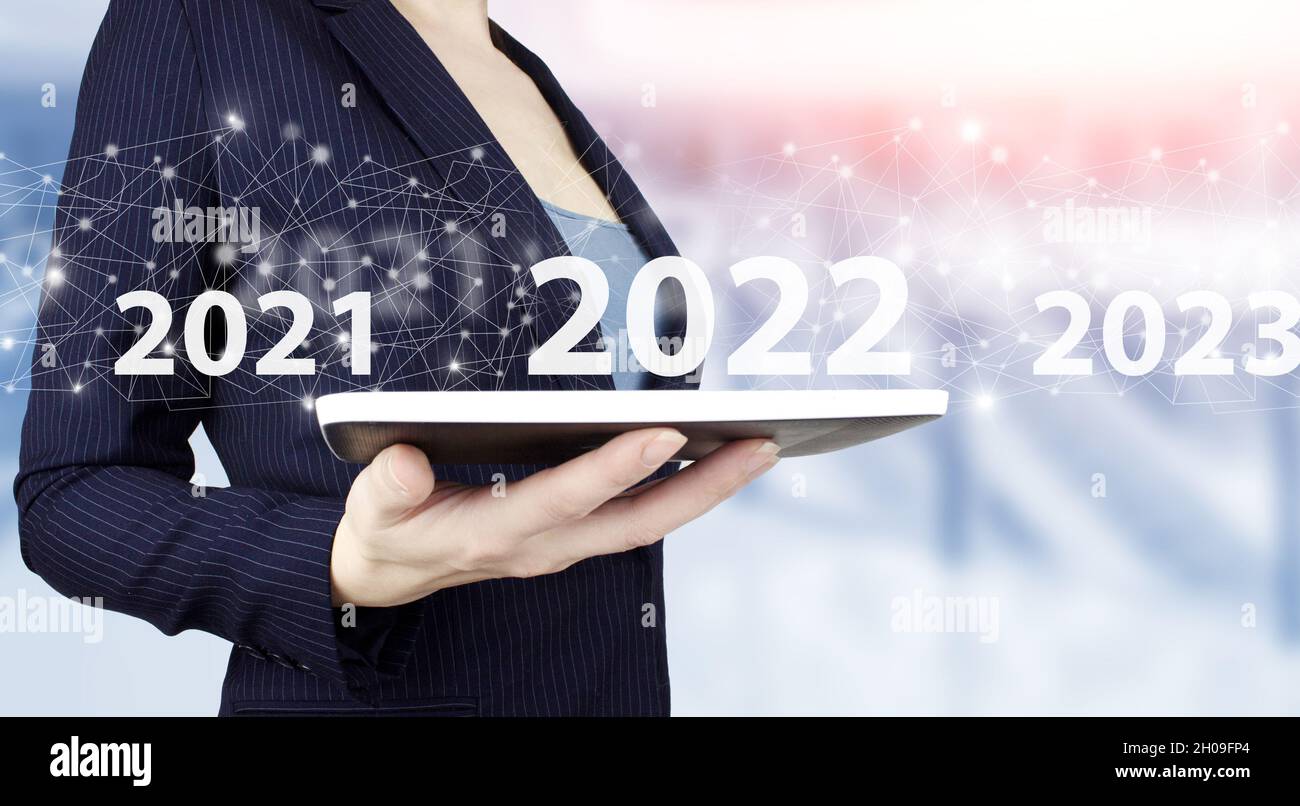 Loading year 2021 to 2022. Start concept. Hand hold white tablet with digital hologram 2022 sign on light blurred background. Concept Start New Year 2 Stock Photo