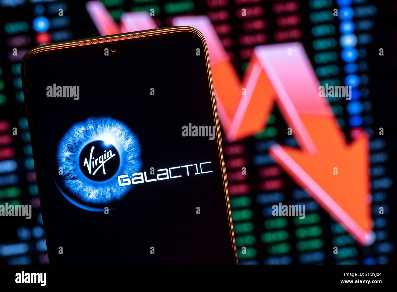Virgin Galactic logo on the background of a large red arrow pointing down. Falling stock price. Stock Photo