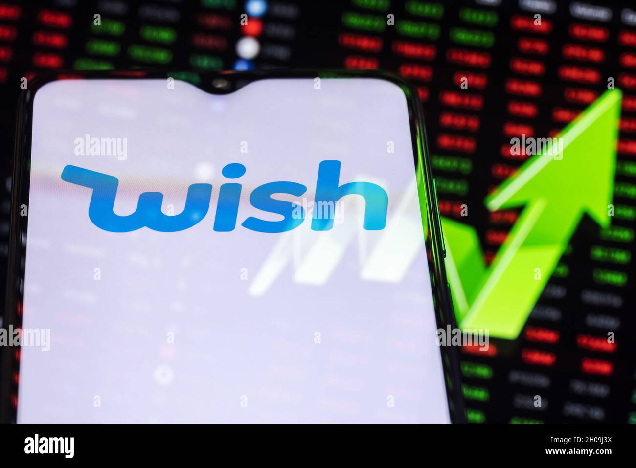 Wish logo on the background of a large green arrow pointing up. Stock Photo
