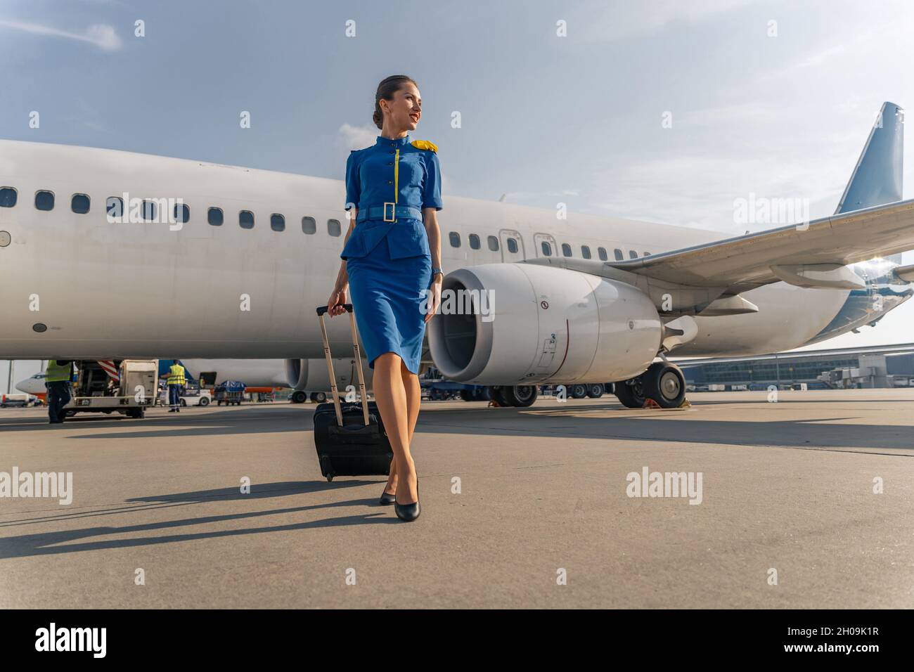 Female flight attendant walking with black suitcase Stock Photo