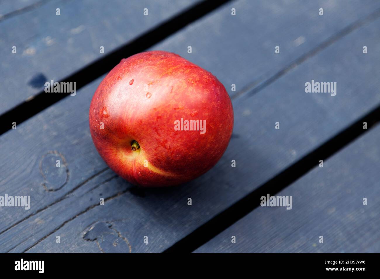 a nectarine lying on a blue cutting board Stock Photo