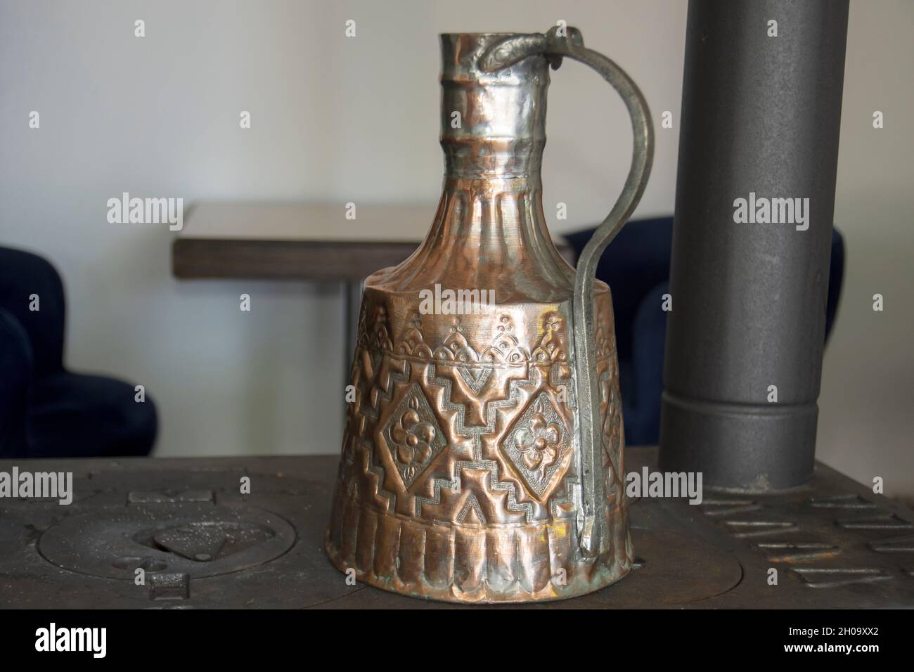 very old copper carved pot used for heating water over a stove Stock Photo