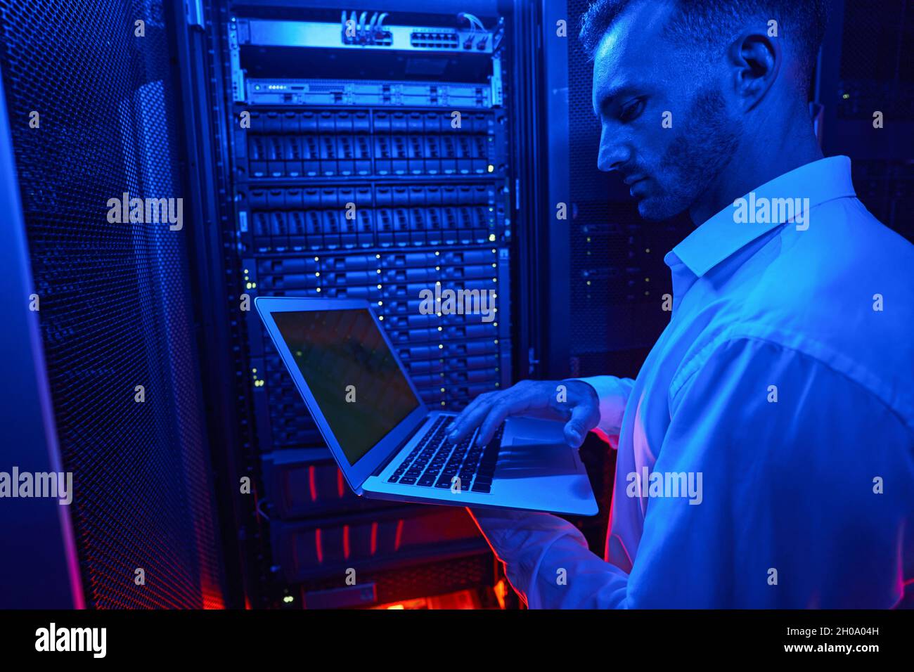 Server engineer with laptop working on data security issues Stock Photo