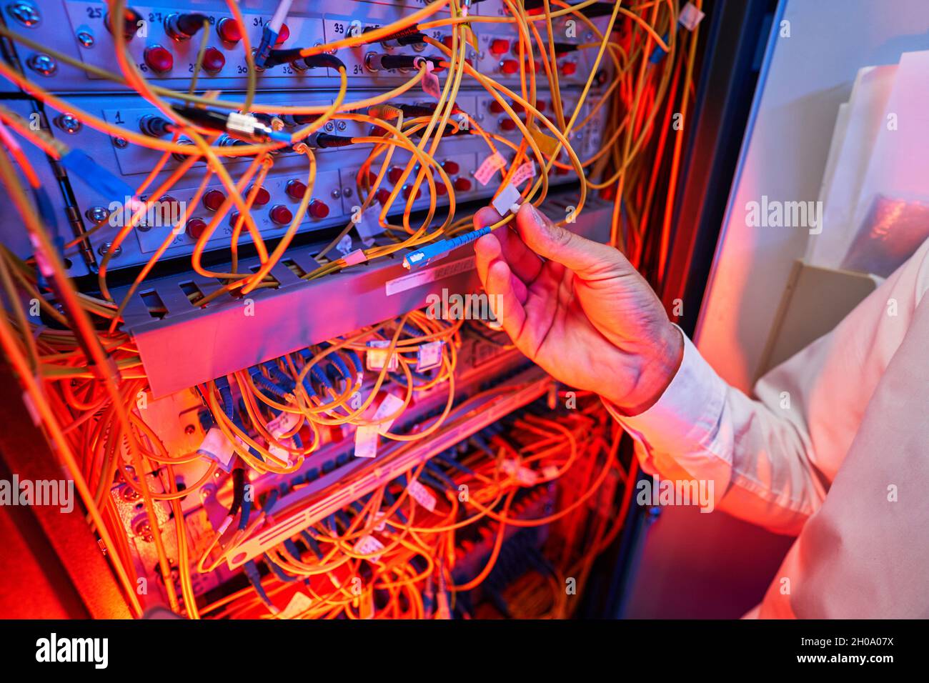 IT engineer connecting fiber-optic cable to server switch Stock Photo