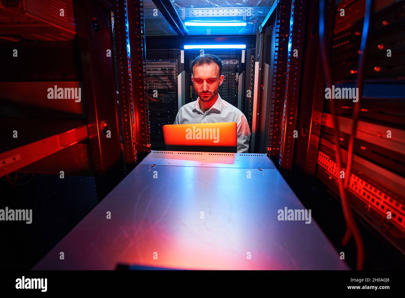 Technician with laptop in front of server rack Stock Photo Alamy