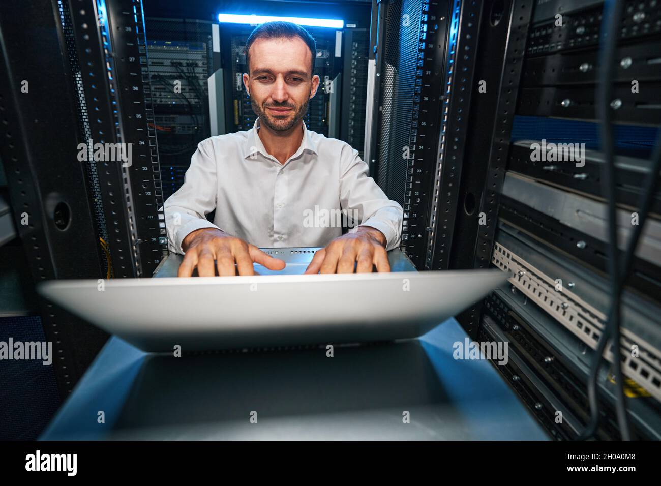 Satisfied data center manager checking network settings with laptop Stock Photo