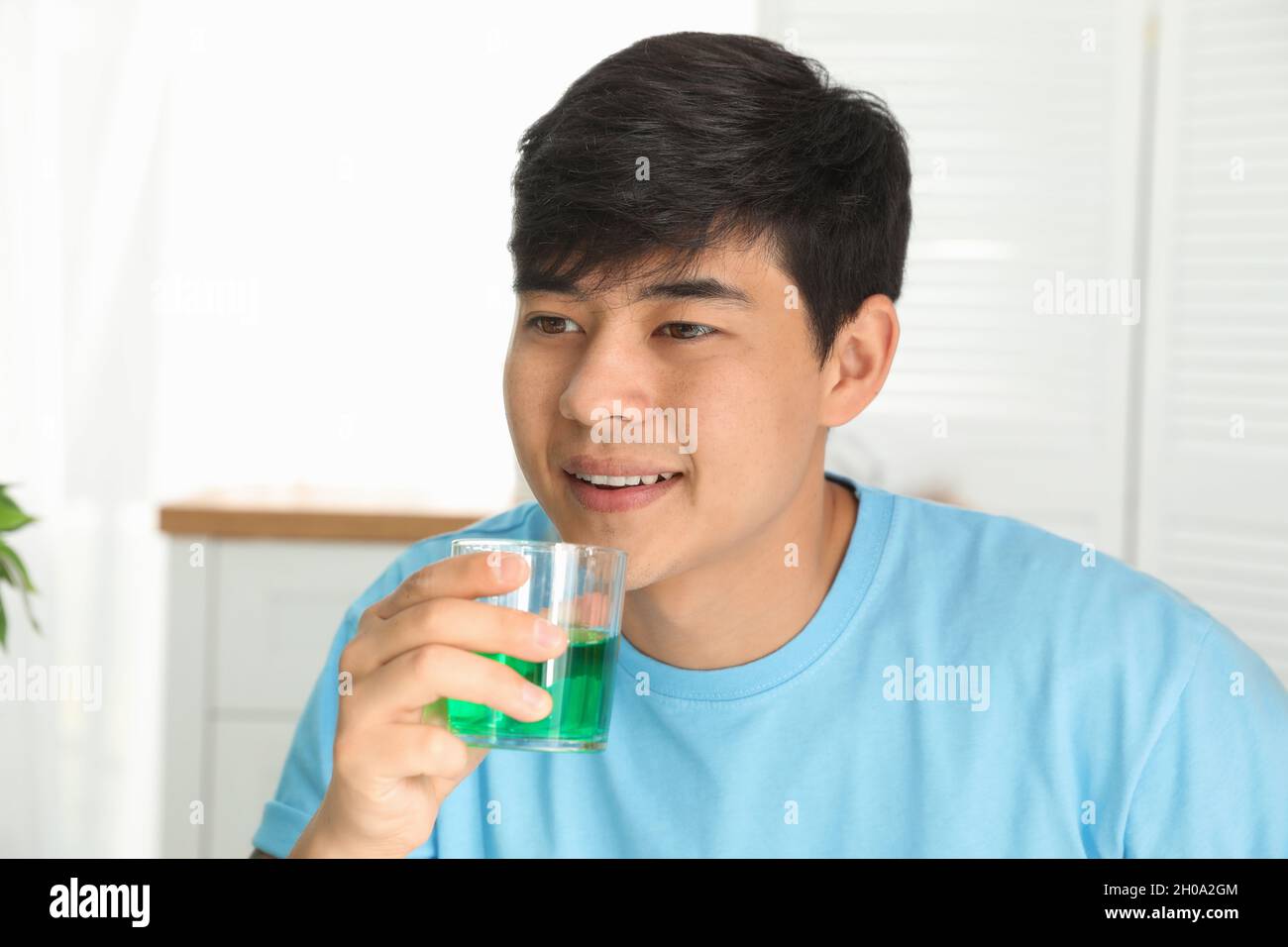 Man holding glass with mouthwash in bathroom. Teeth care Stock Photo