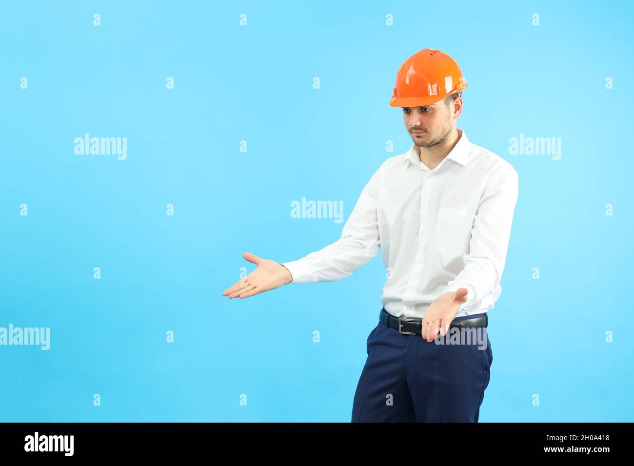 Businessman builder in misunderstanding on blue background. Stock Photo