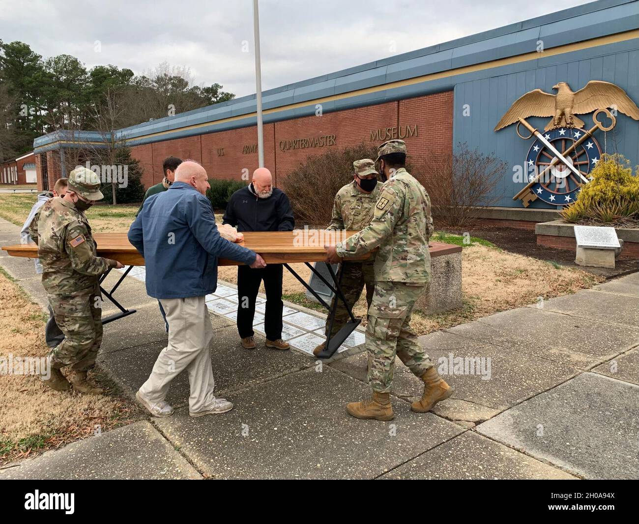 Volunteers carry an M-1903 mess hall table into the Quartermaster Museum Jan. 5. The furniture piece was discovered in a facility workshop by Lee Holland (blue jacket), who donates his time to the museum. After learning of its historical significance, he spent 100 hours restoring the piece so it could be displayed as part of an exhibit. Stock Photo