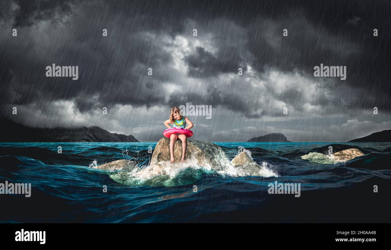 little girl with lifebuoy sitting on a rock during a storm. Stock Photo