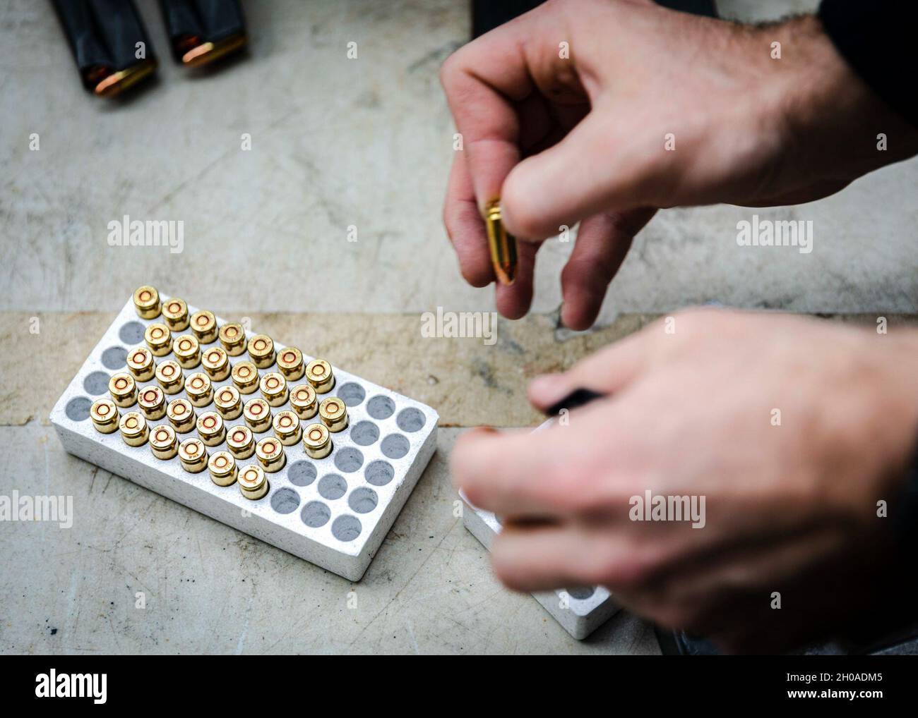 Sailors load ammunition into an M9 service pistol magazines during a