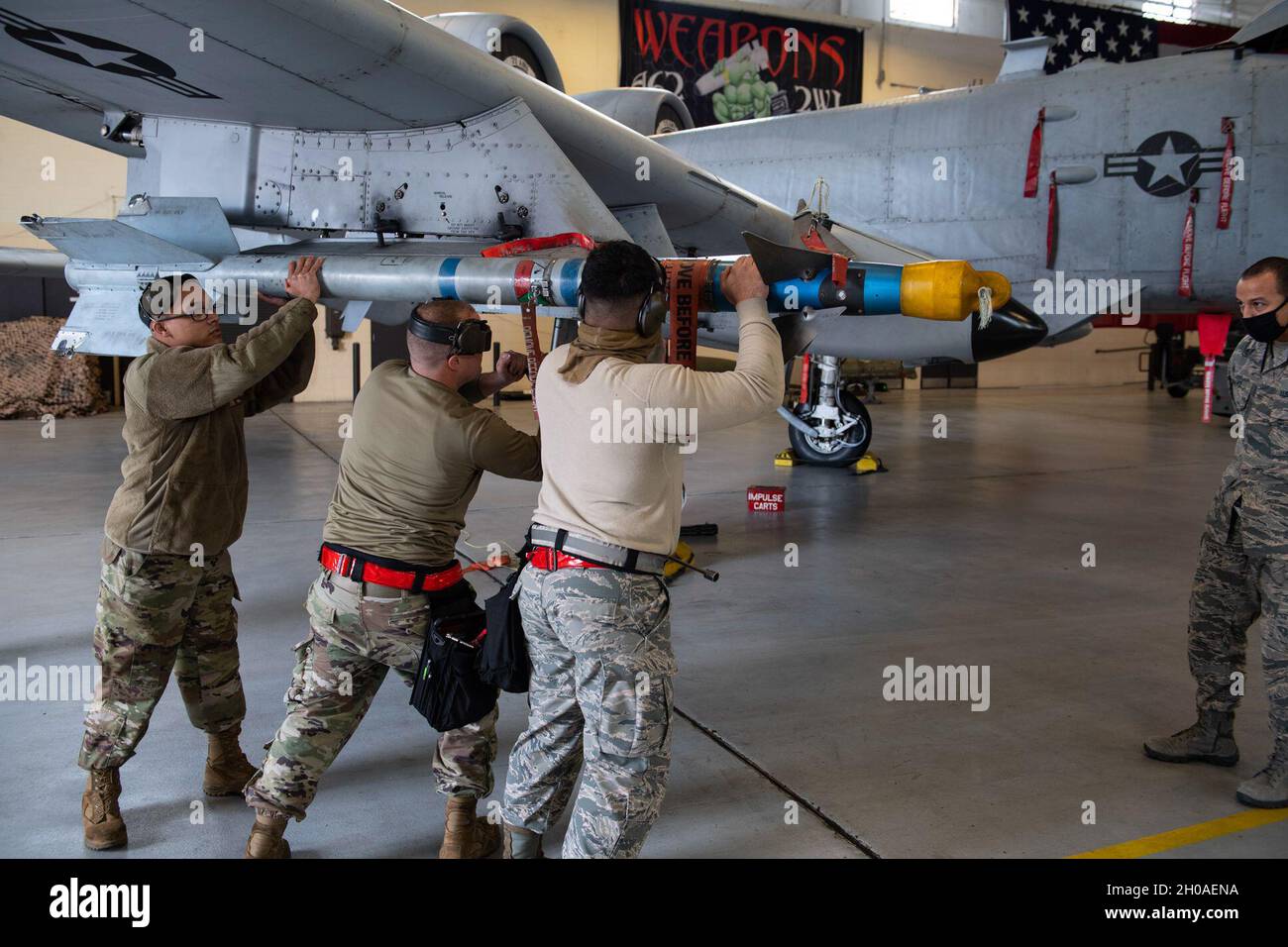 Airmen assigned to the 75th Aircraft Maintenance Unit load an AIM-9 ...