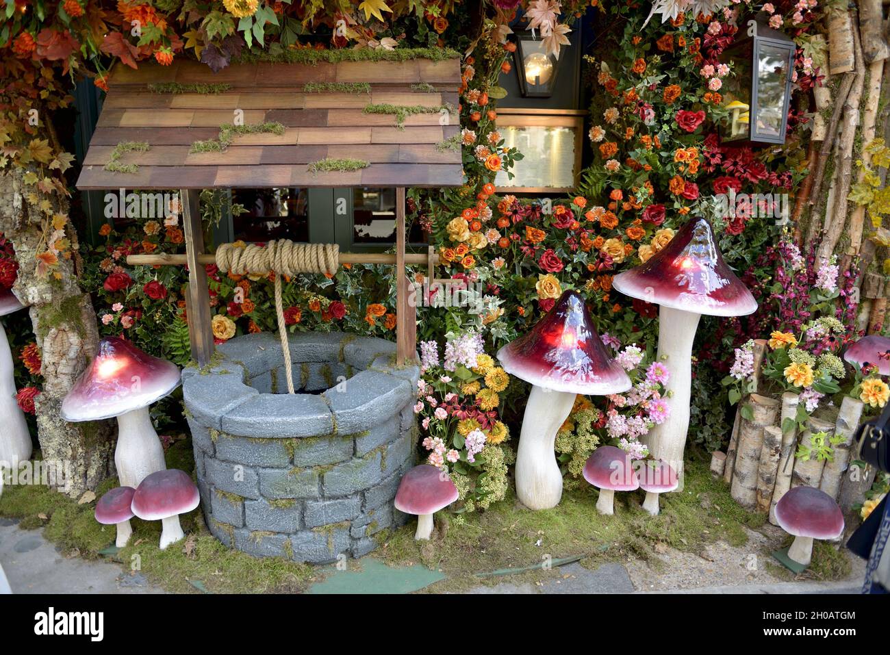 Wishing well and giant mushrooms outside a shop in the King's Road during Chelsea in Bloom annual floral art show and flower shower in the shops and s Stock Photo