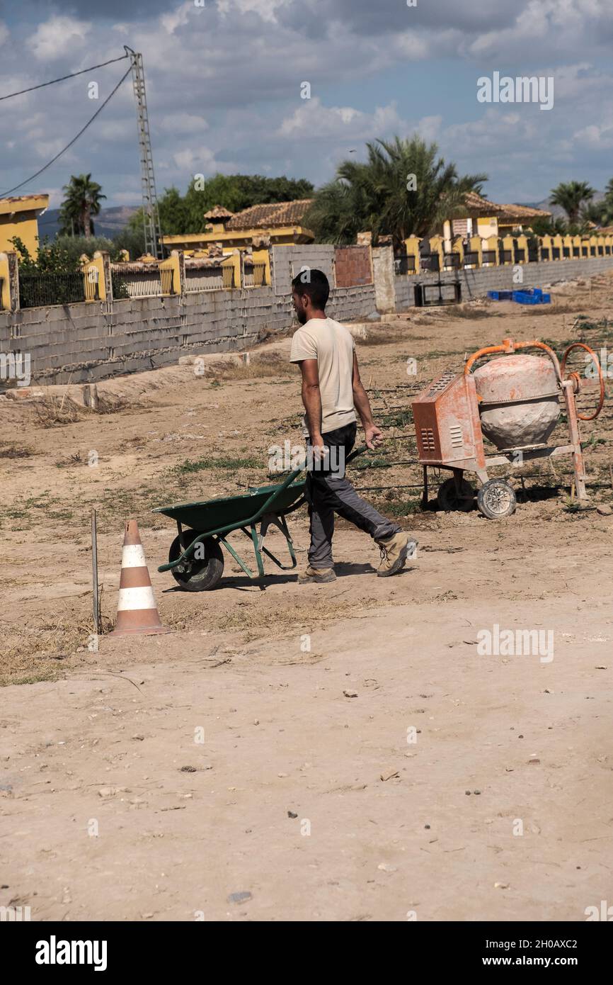 Young worker transporting materials with a wheelbarrow. Effort concept. Stock Photo