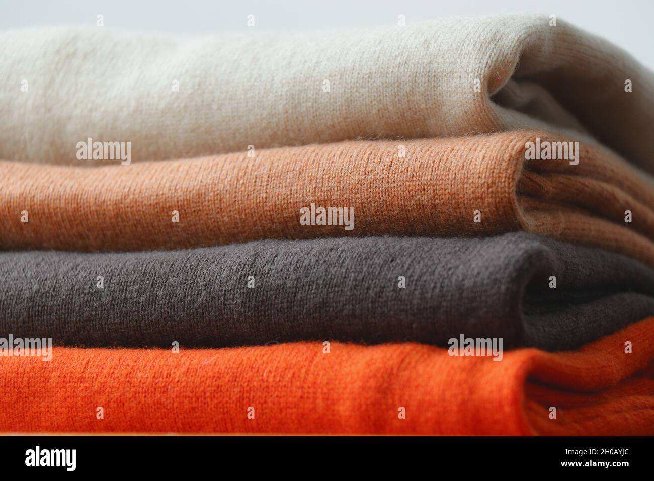 Pile or stack of fall colour, folded cashmere or merino wool jumpers. Stock Photo