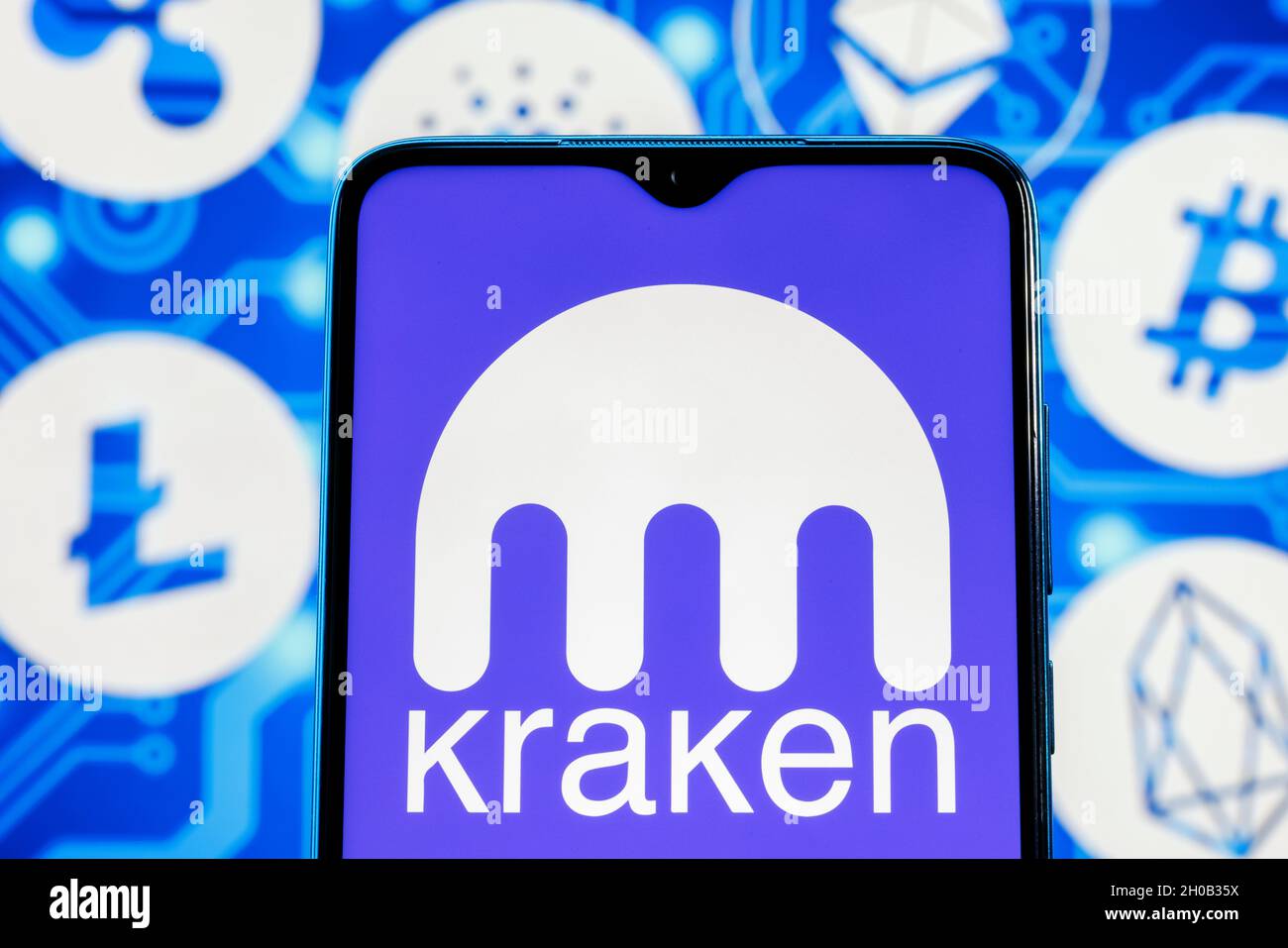 Kraken is cryptocurrency exchange. Kraken logo on smartphone screen against the background of the main cryptocurrencies. Stock Photo