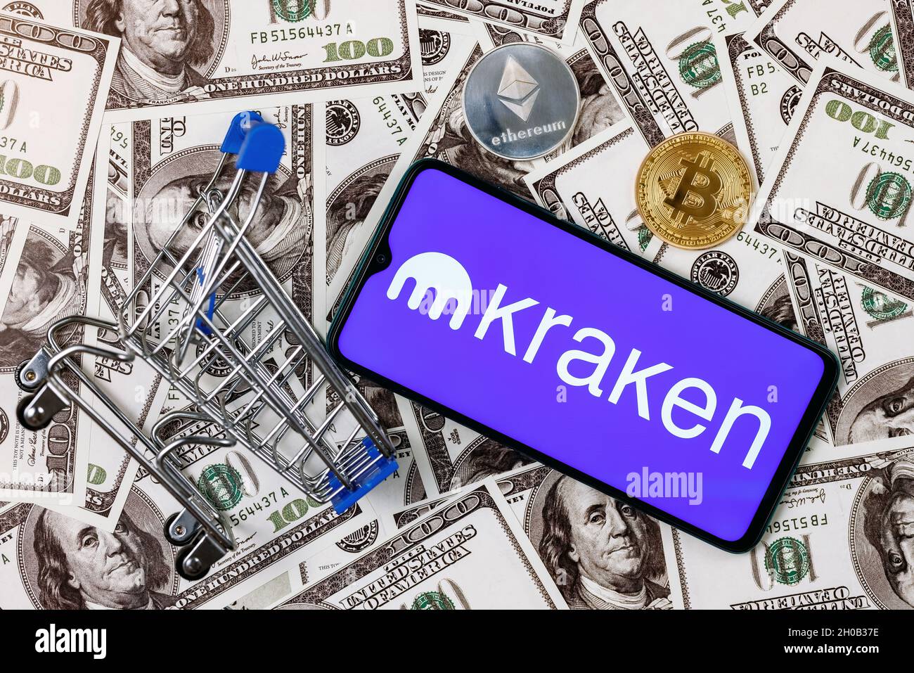 A smartphone with the Kraken logo, a shopping cart and a cryptocoins on the  dollar bills Stock Photo - Alamy