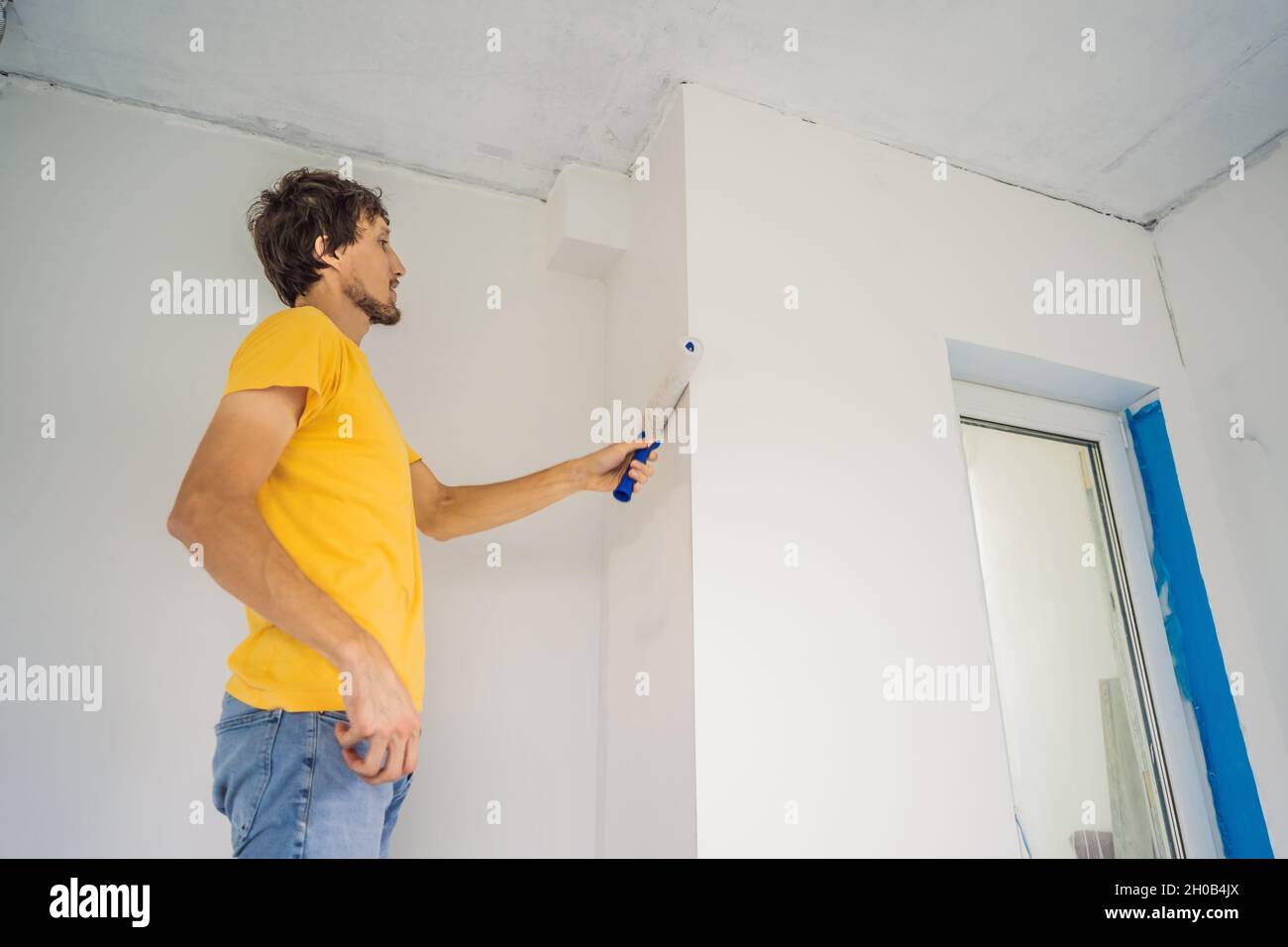 One male house painter worker painting and priming wall with painting