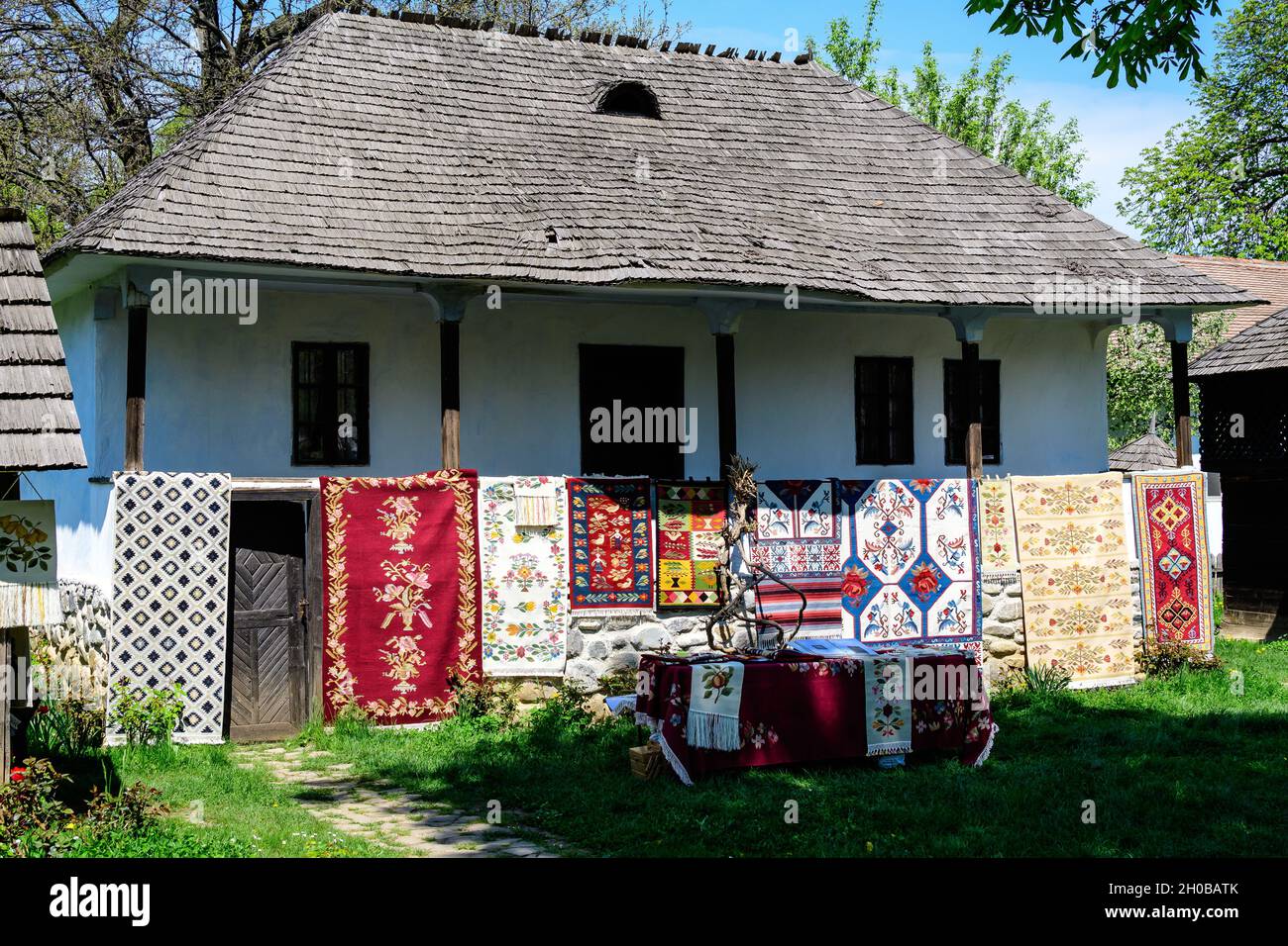 Bucharest, Romania - 25 April 2021: Old traditional Romanian house surounded with many old trees and green grass in Dimitrie Gusti National Village Mu Stock Photo