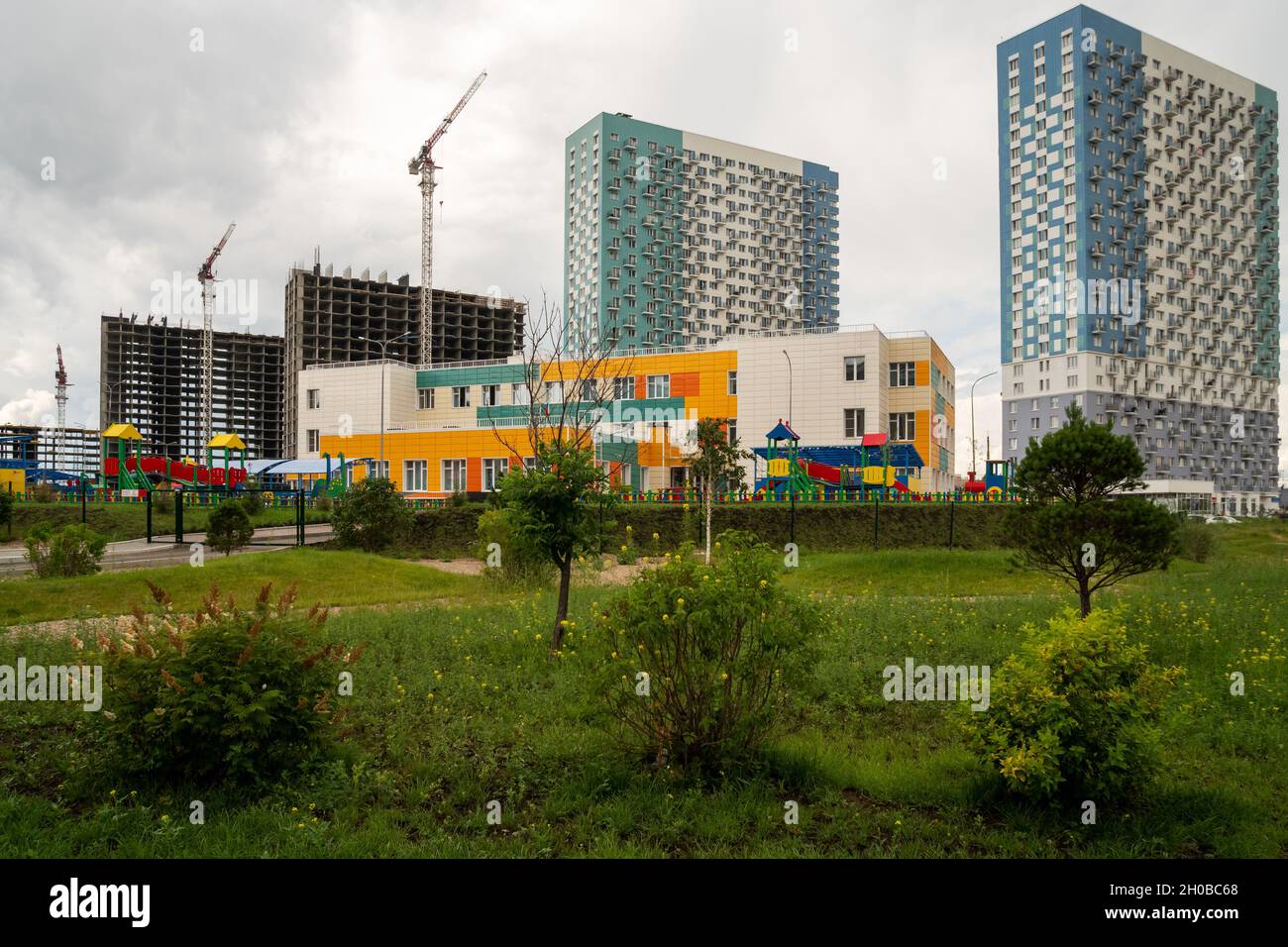View of the recently built municipal kindergarten against the backdrop of new and under construction houses in the Preobrazhensky residential complex, Stock Photo