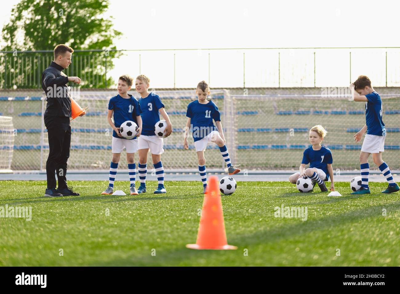 Group of Boys on Soccer Training Field. Young Coach Explaining Drills Rules to Kids on Football Practice. Children on School Sports Class with Trainer Stock Photo