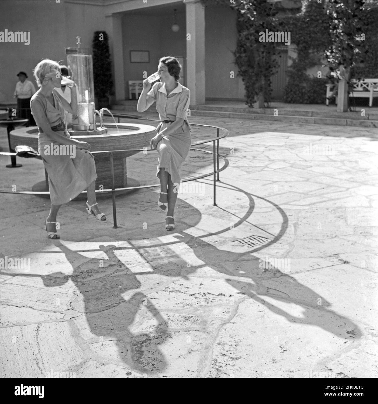 Zwei Frauen trinken aus dem Wilhelmsbrunnen in Bad Cannstatt, Deutschland 1930er Jahre. Two women drinking water from the Wilhelmsbrunnen well at Bad Cannstatt, Germany 1930s. Stock Photo