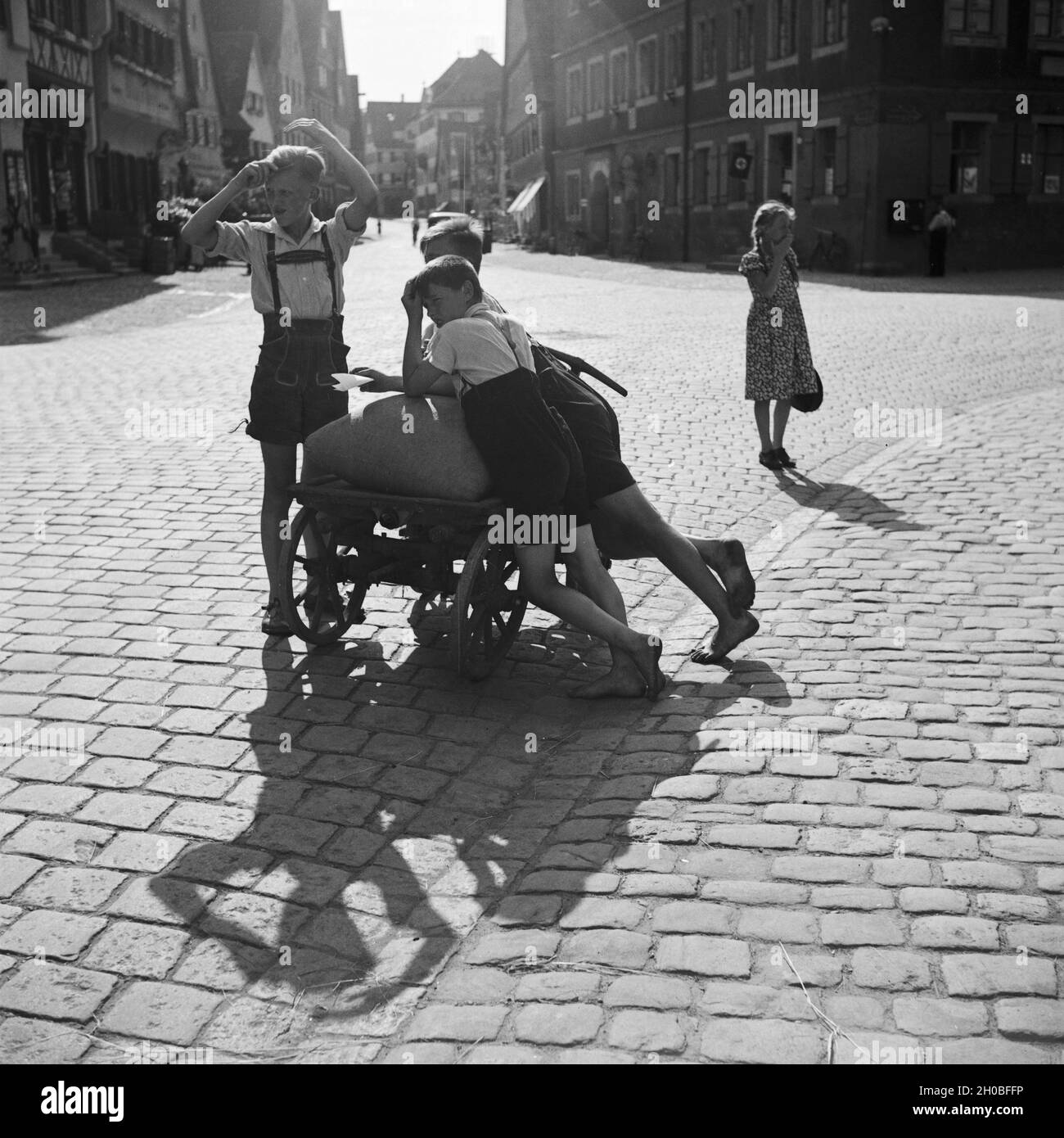 Jungen mit einem Handkarren in einer Straße in Dinkelsbühl, Deutschland 1930er Jahre. Boys with a push cart in a street of Dinkelsbuehl. Germany 1930s. Stock Photo