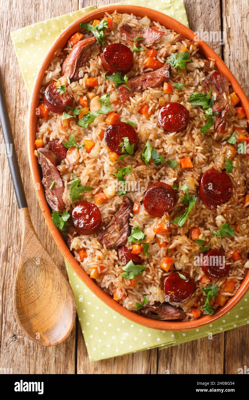 Arroz de pato or duck rice is a traditional Portuguese food close up in the baking dish on the wooden table. Vertical top view from above Stock Photo