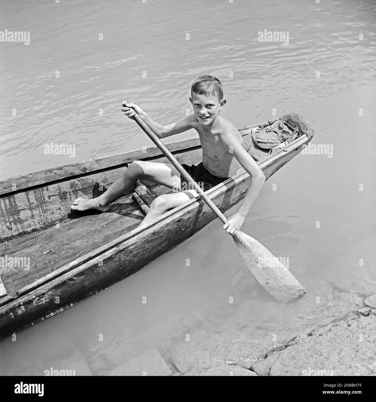Ein kleiner Junge in seinem traditionellen Ruderboot auf der Donau bei Passau, Deutschland 1930er Jahre. A little boy in his traditinal rowing boat on river Danube near Passau, Germany 1930s. Stock Photo