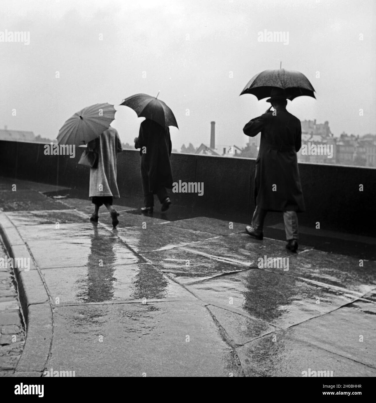 Menschen an einem Regentag unterwegs mit ihren Regenschirmen, Deutschland 1930er Jahre. People on a rainy day on their way with their umbrellas, Germany 1930s. Stock Photo