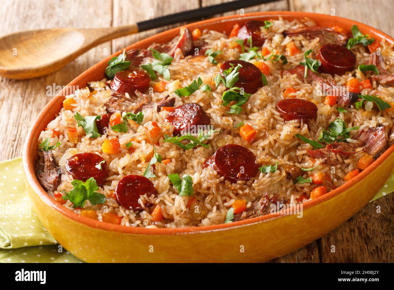 Portuguese duck rice arroz de pato cooked with red wine, onion, carrot and chorizo close up in the baking dish on the wooden table. Horizontal Stock Photo