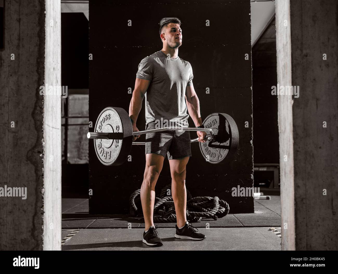 Young Caucasian in sportswear lifting weights. Make muscles not excuses. Stock Photo