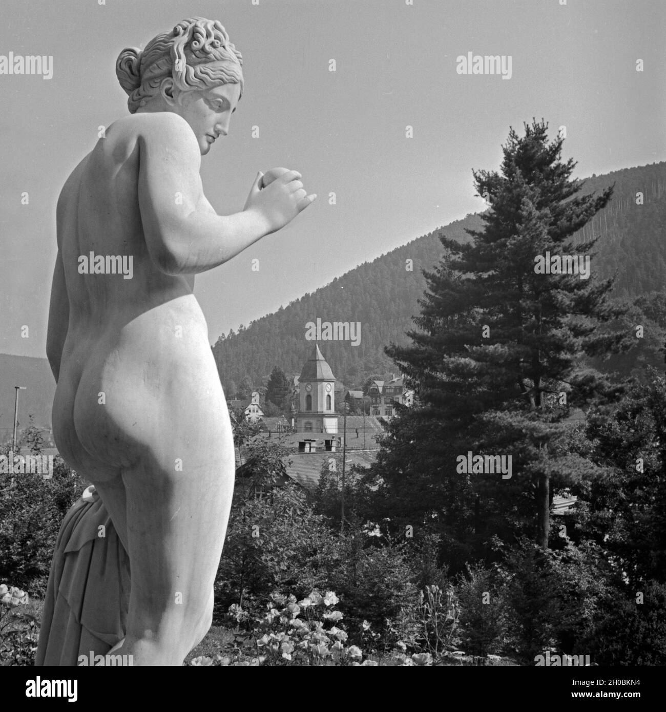 Frauenstatue vor der Stadtansicht von Wildbad im Schwarzwald, Deutschland 1930er Jahre. Sculpture of a female in front of the town of Wildbad in Black Forest, Germany 1930s. Stock Photo