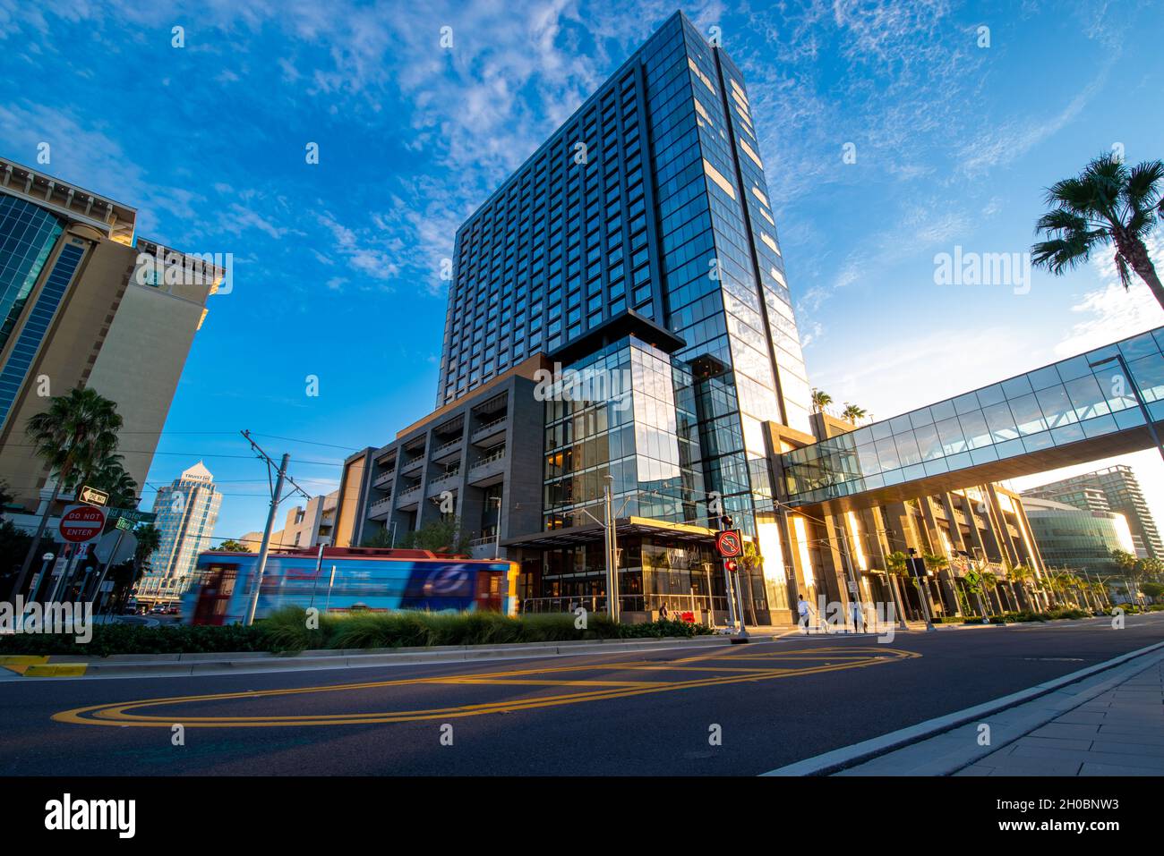 Tampa, FL—Sept 12, 2021; early morning low angle view of the mirrored windowed JW Marriott hotel downtown with TECO trolly in front and pedestrian bri Stock Photo