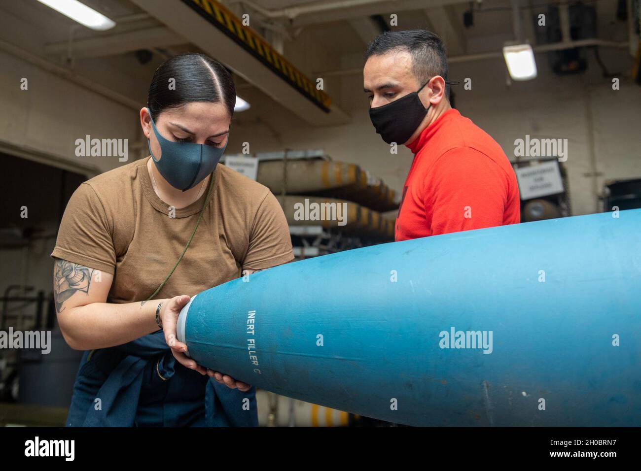 210121-N-QM903-1003 PHILIPPINE SEA (Jan. 21, 2021) Aviation Ordnanceman Airman Mariangelys Ojeda Marrero, left, from Puerto Rico, assigned to the forward-deployed amphibious assault ship USS America (LHA 6), inserts a nose plug into an inert practice bomb, while Aviation Ordnanceman 2nd Class Rafael Gonzalez Borras, from Miami, also assigned to USS America, supervises. America, flagship of the America Expeditionary Strike Group, along with the 31st Marine Expeditionary Unit, is operating in the U.S. 7th Fleet area of responsibility to enhance interoperability with allies and partners, serving Stock Photo