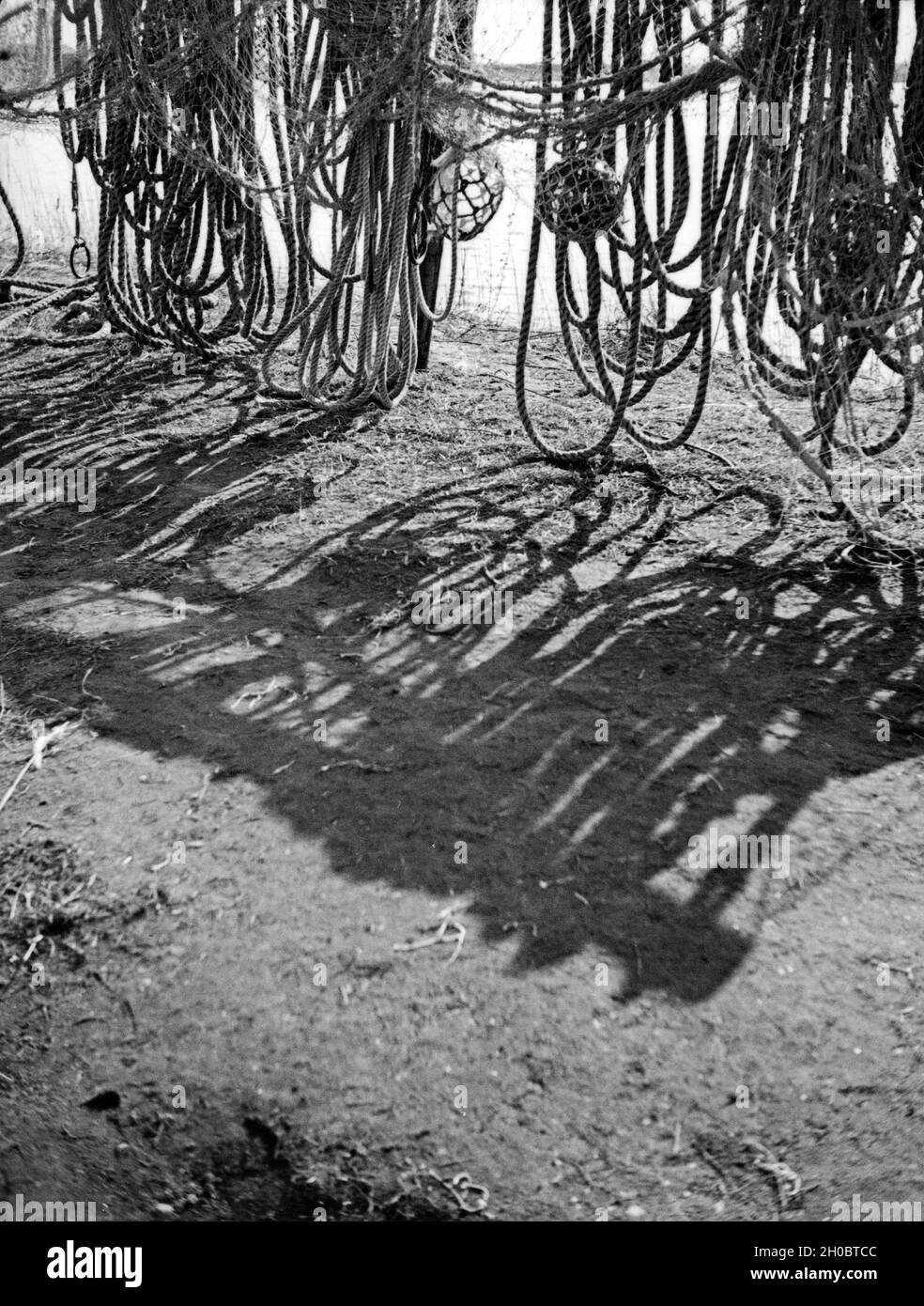 Tauwerk wirft seinen Schlagschatten vor einem Fischerhaus in Ostpreuen, 1930er Jahre. Hemp rope and its shadows in front of a fisherman's house in East Prussia, 1930s. Stock Photo