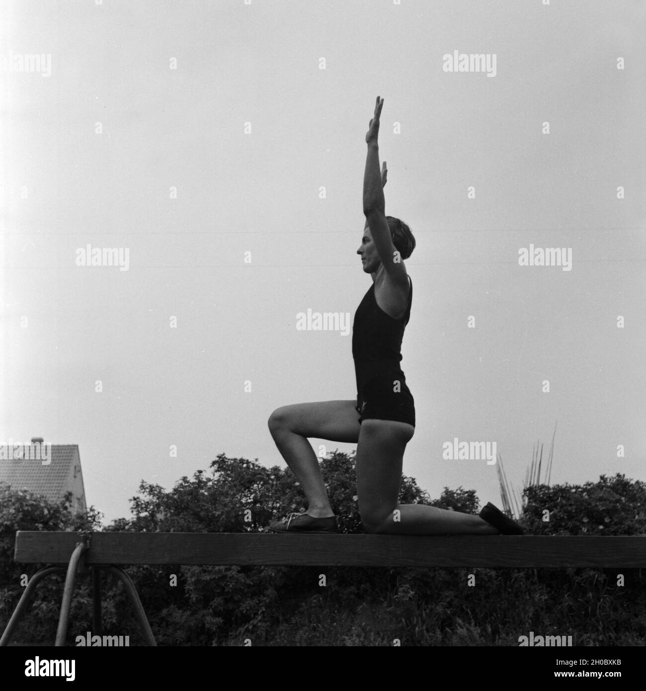 Eine Frau bei einer Übung am Schwebebalken in der Logau Musterschule für Frauenturnen in Hannover, Deutschland 1930er Jahre. A woman doing an exercise at the balance beam at the Logau school for women's gymnastics in Hanover, Germany 1930s. Stock Photo