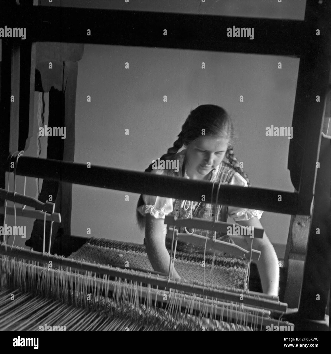 Ein Mädchen an einem Webstuhl im Landjahr Lager in Polle an der Weser, Deutschland 1930er Jahre. A girl weaving at a loom at the BdM camp at Polle, Germany 1930s. Stock Photo