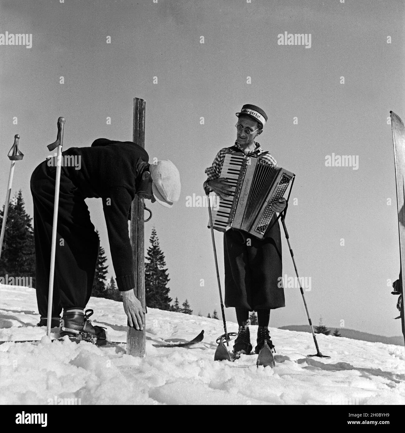 Der Akkordeonspieler vom Hotel Feldbergerhof begleitet die Skifahrer bei ihrem Sport, Deutschland 1930er Jahre. The accordion player accompanies the ski tourists at their sports, Germany 1930s. Stock Photo