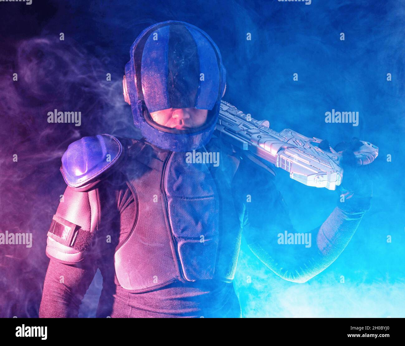 Cyberpunk future concept. Police officer reloads futuristic shotgun in dark. Robot aims at camera. Halfman bionic cyborg releases disconnector assembl Stock Photo