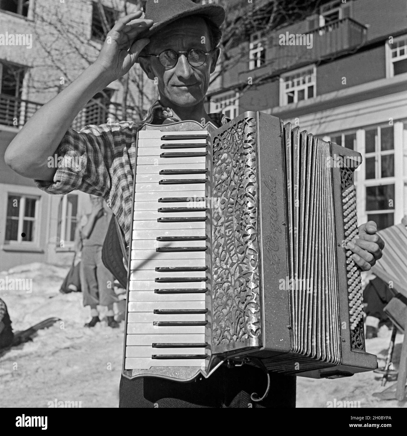 Der Akkordeonspieler vom Hotel Feldbergerhof begleitet die Skifahrer bei ihrer Freizeit, Deutschland 1930er Jahre. The accordion player accompanies the ski tourists at their leisure time Germany 1930s. Stock Photo
