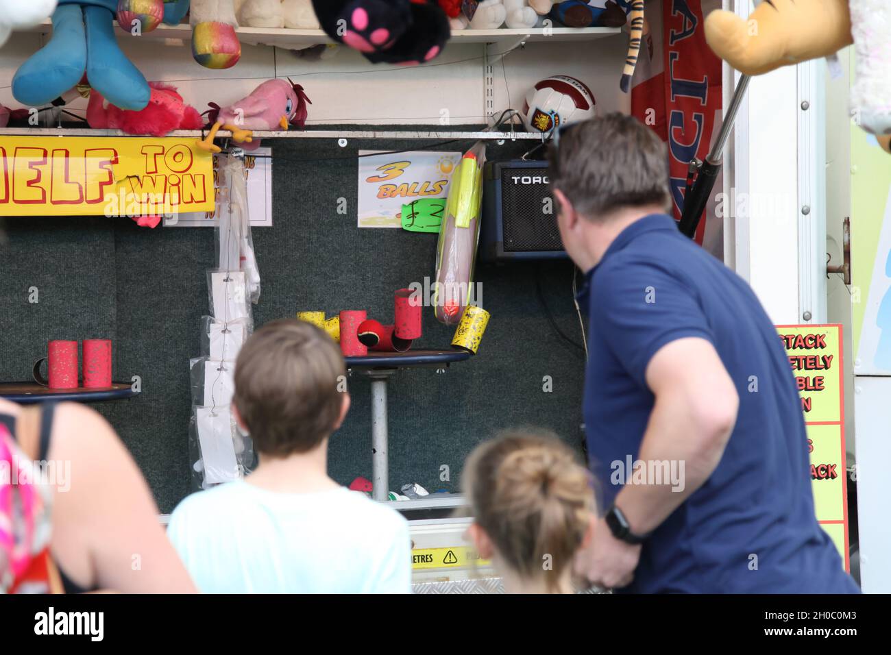 A man throwing ball at cans, tin can alley, Leatherhead Fun fair July 2021 Stock Photo