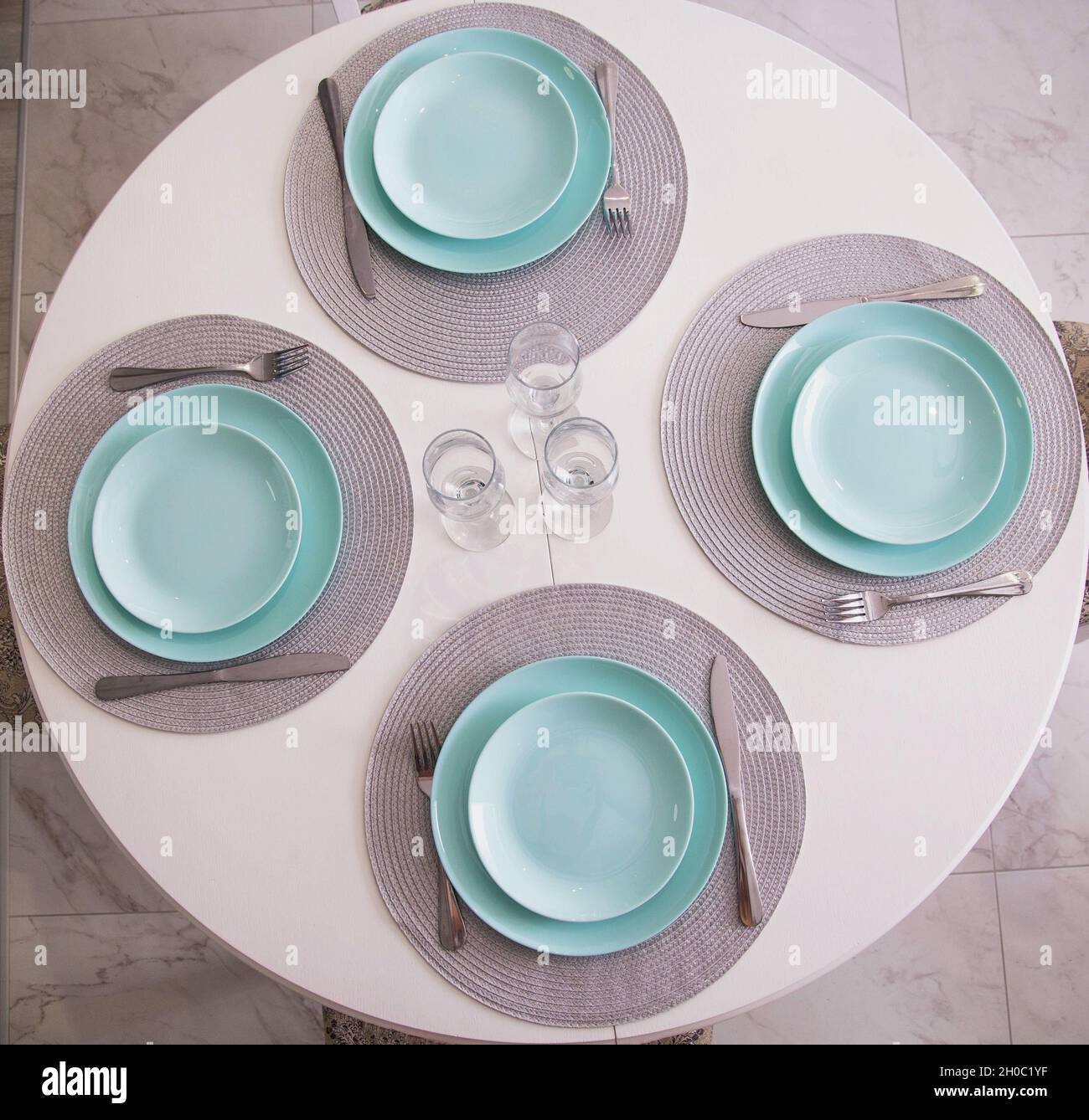 Kitchen table setting with turquoise plates and glasses. Cutlery on ...