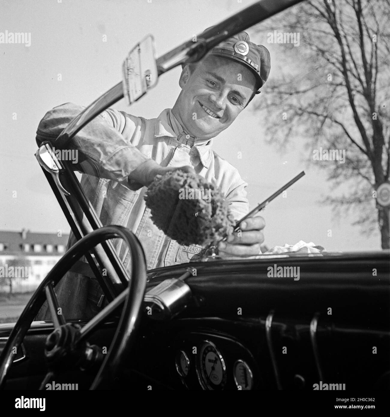 Der freundliche Tankwart putzt die Windschutzscheibe, Deutschland 1930er Jahre. Perfect customer service at the petrol station, Germany 1930s. Stock Photo